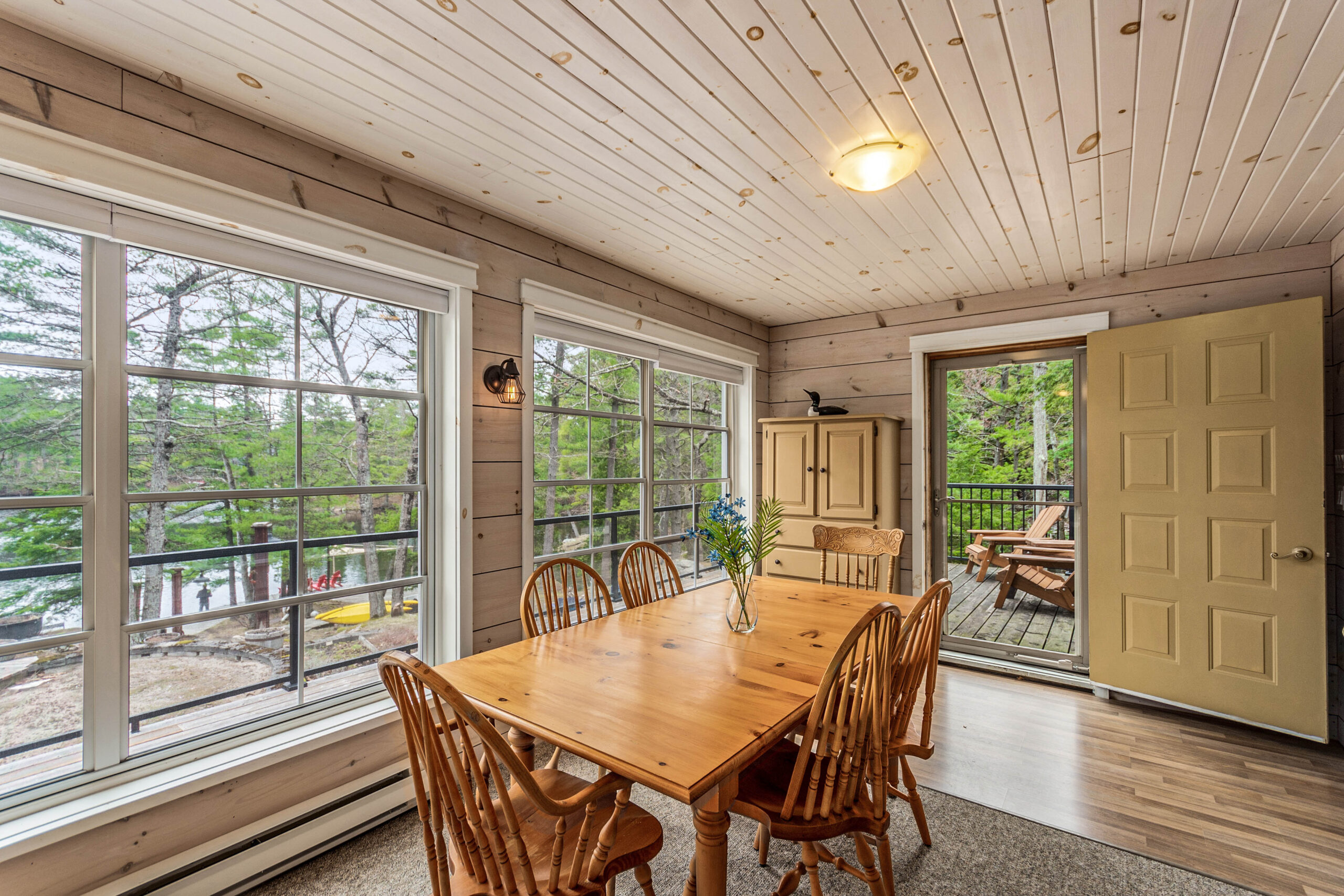 A wood dining table with wood chairs in a bright sunroom