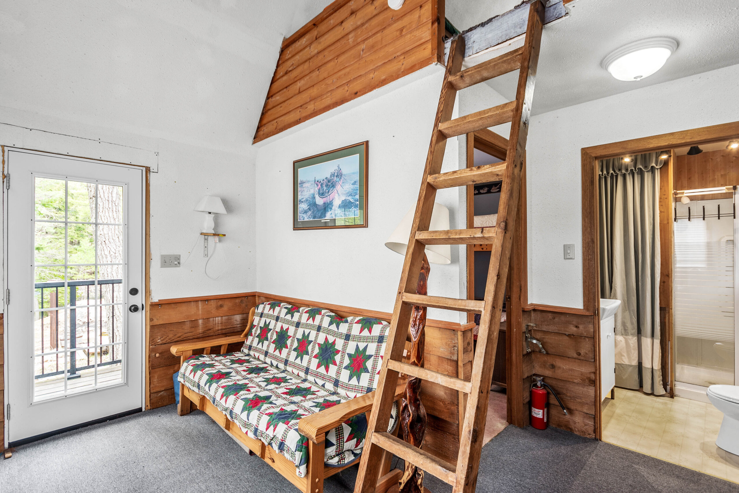 A white room with a patterned couch and a wood ladder
