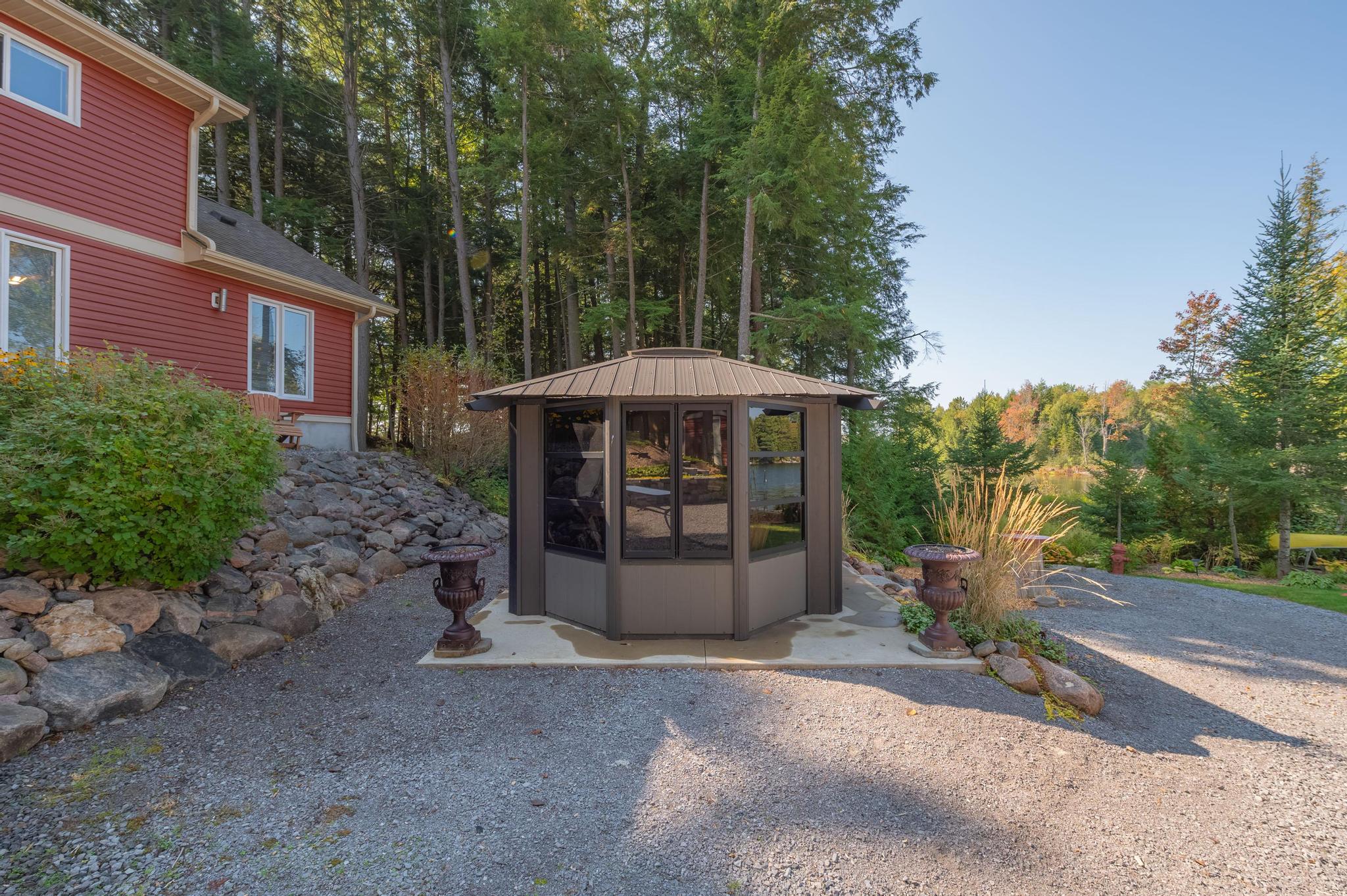A spacious parking area with a red cottage in the background, nestled among trees.
