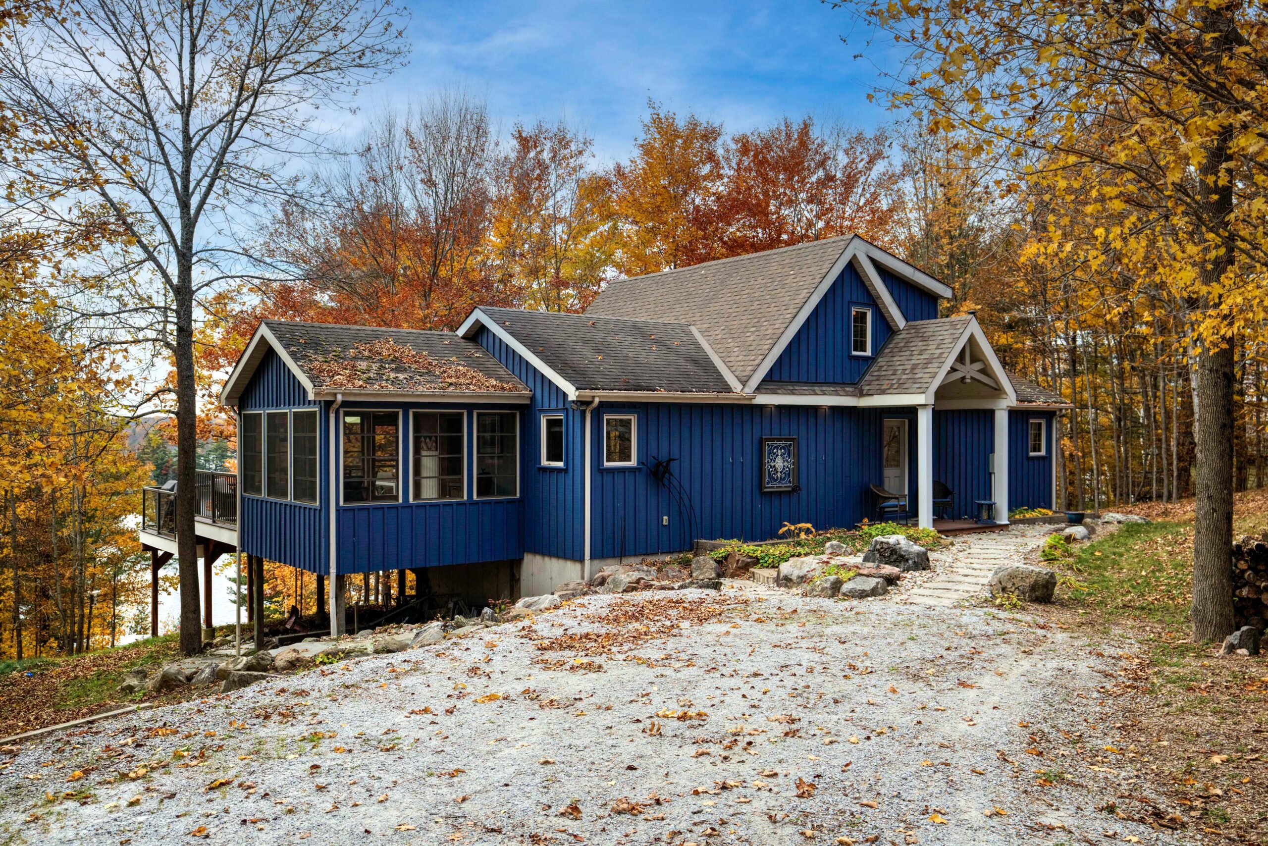 A blue cottage with a brown rood with a long driveway
