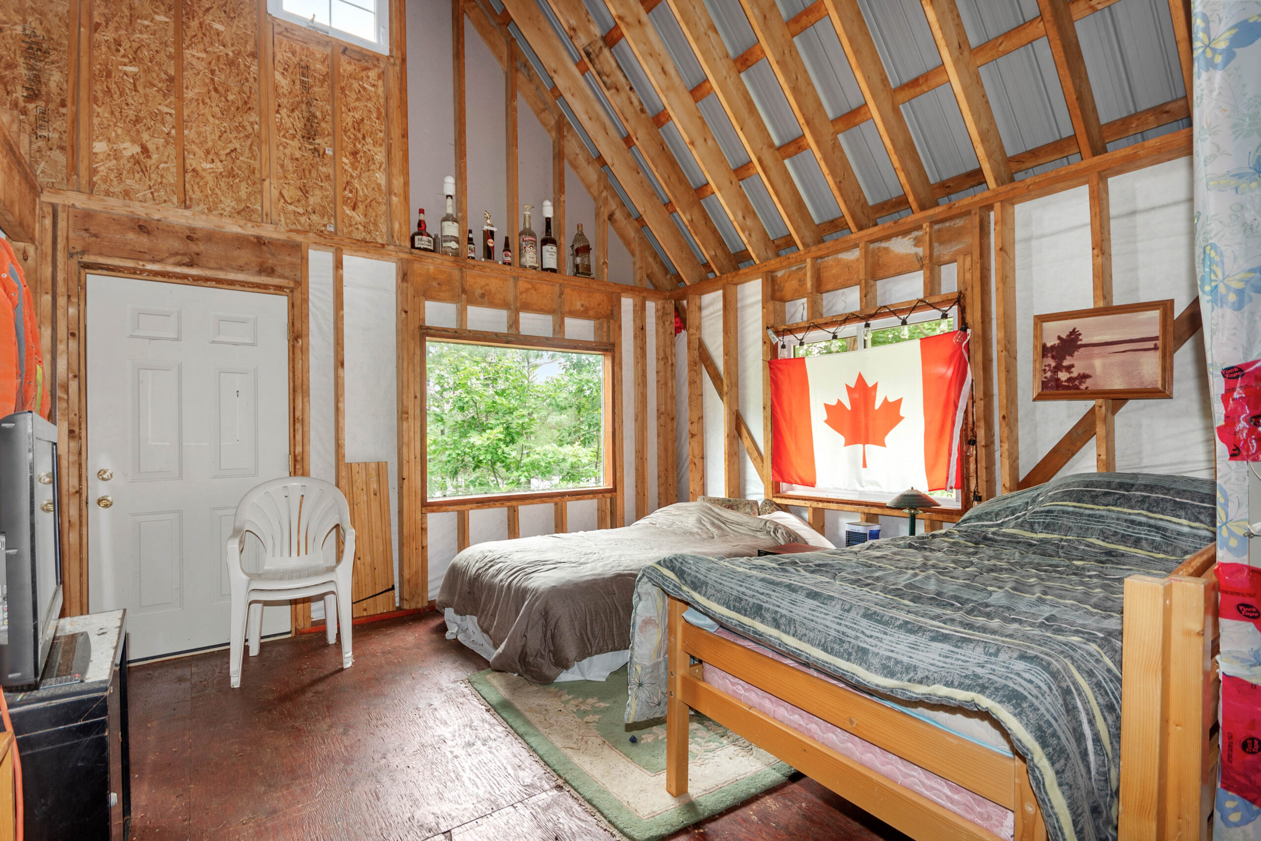 Two beds with a Canada flag hanging behind in a wood room