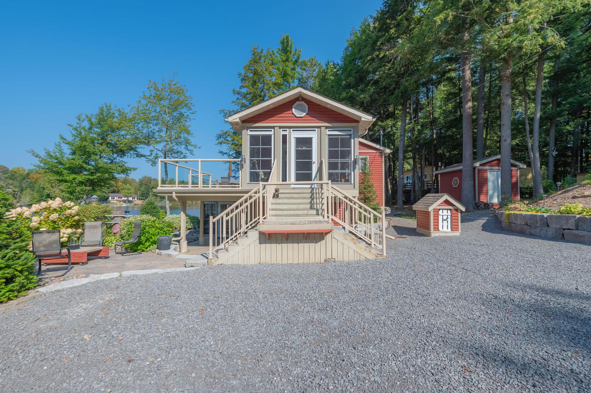 A cozy wooden gazebo with outdoor seating, surrounded by lush greenery and overlooking the lake.
