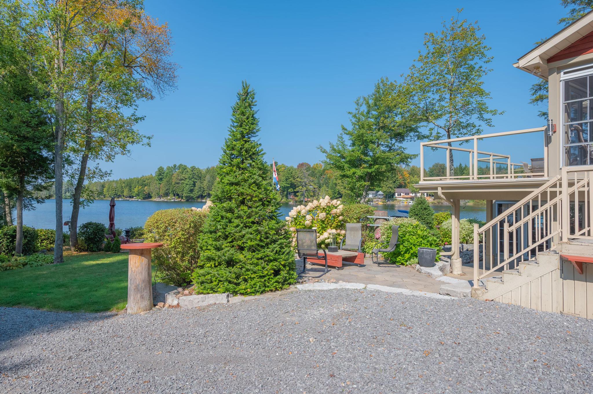 A well-manicured front yard with a stone pathway leading to the lake, framed by beautiful gardens.