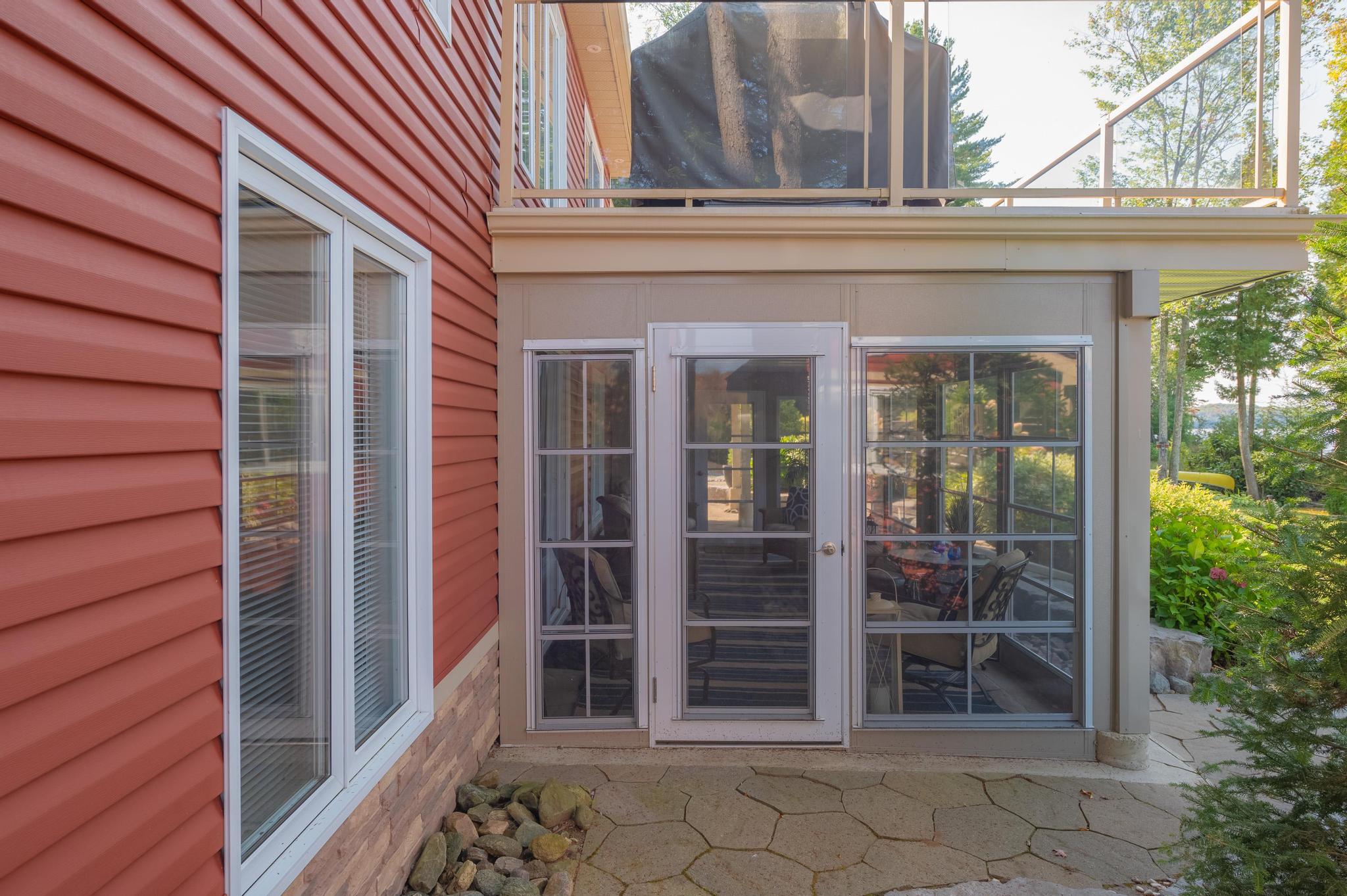 A charming entrance to the red cottage, featuring a covered porch with glass windows.