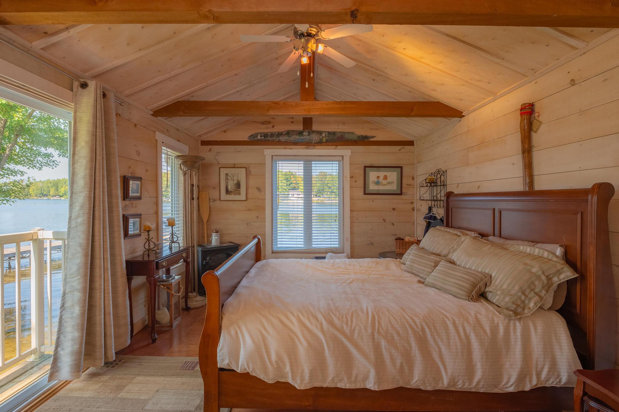 A warm and inviting bedroom with wooden ceilings, a comfortable bed, and large windows.