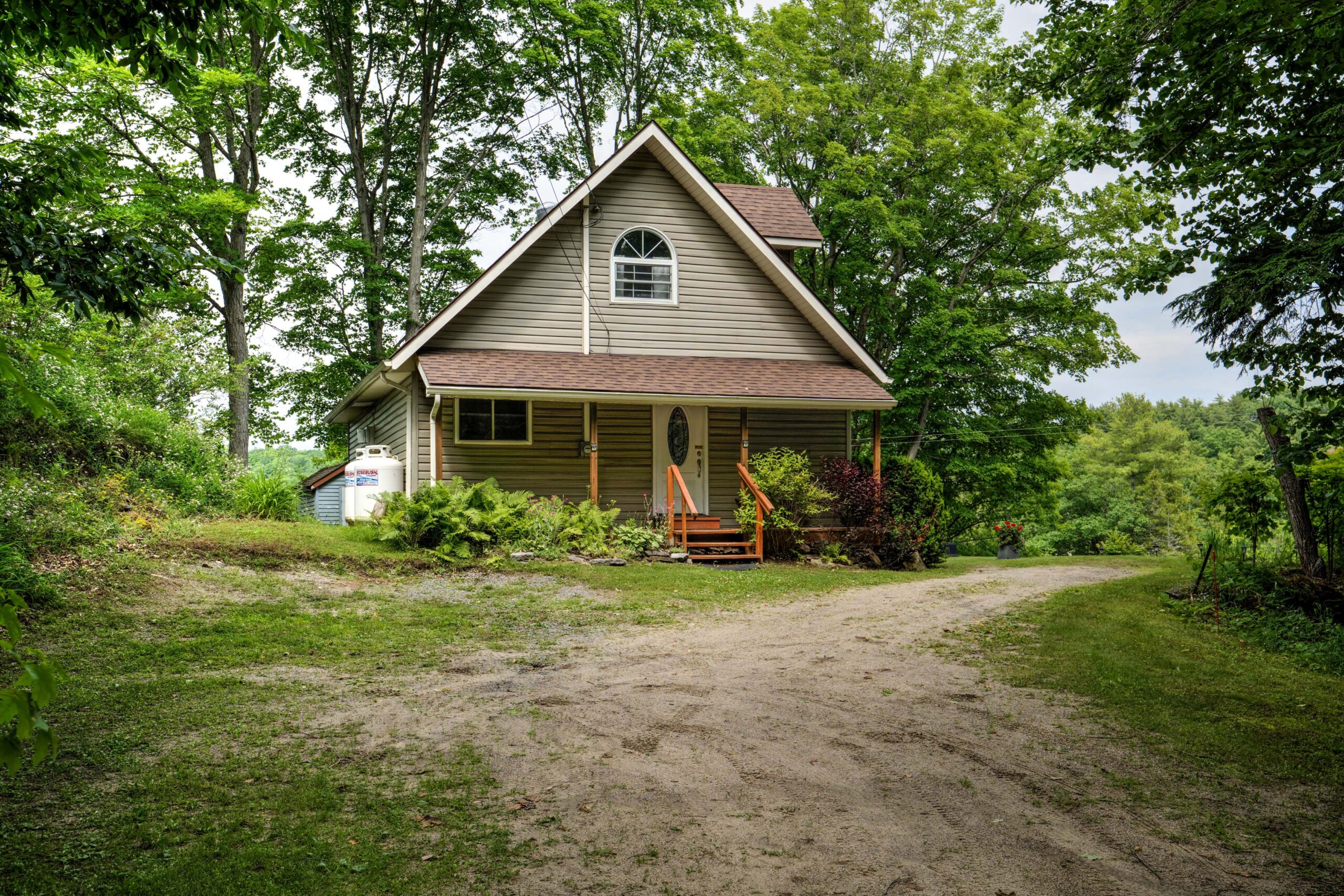 A paneled-cottage with an A-frame-style upper-level