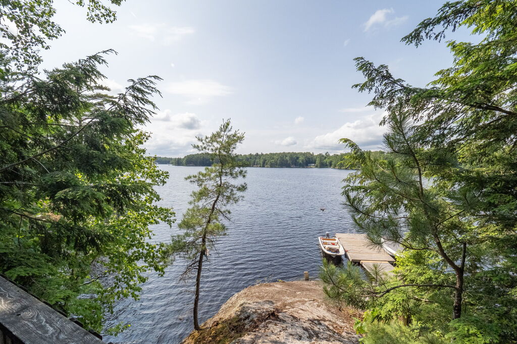 Clear view of Kahshe Lake framed by evergreens on rocky shoreline