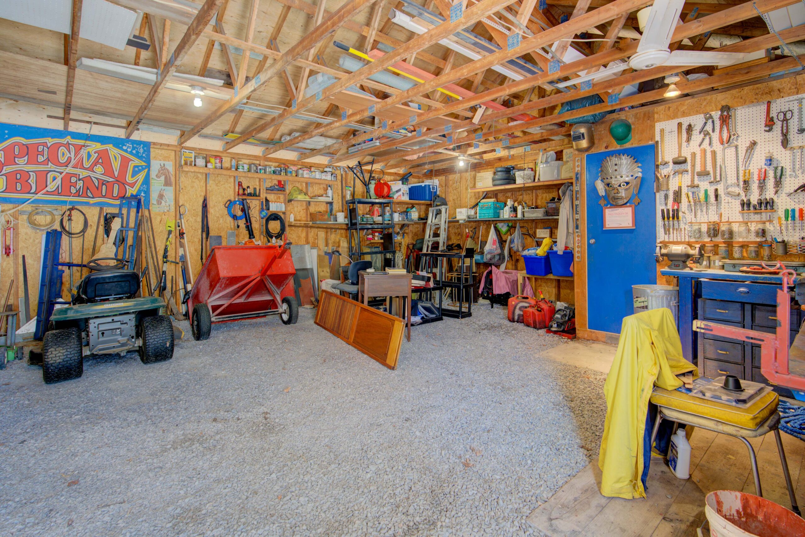 A n unfinished garage with vaulted wood ceilings has tons of odds and ends scattered around