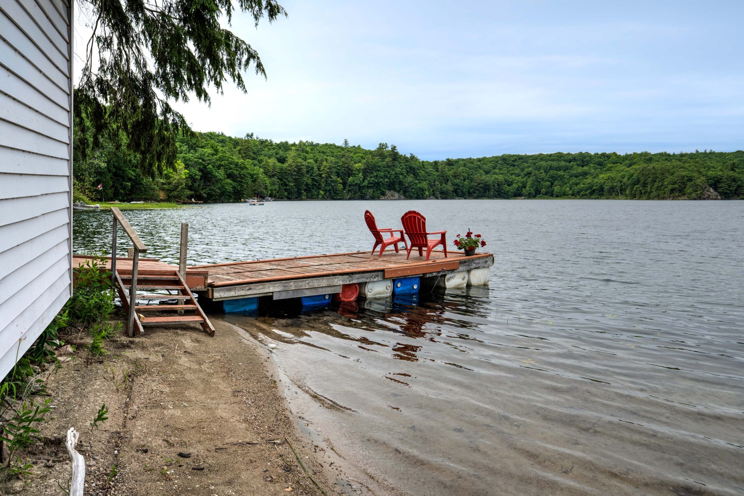 A dock juts out from the sandy beach into the lake