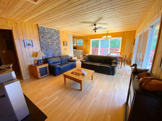 Two black leather couches face a wood coffee table in a wood-paneled room