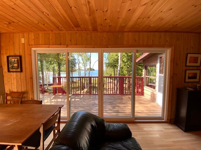 Glass sliding doors in a wood-paneled room lead to a wood deck