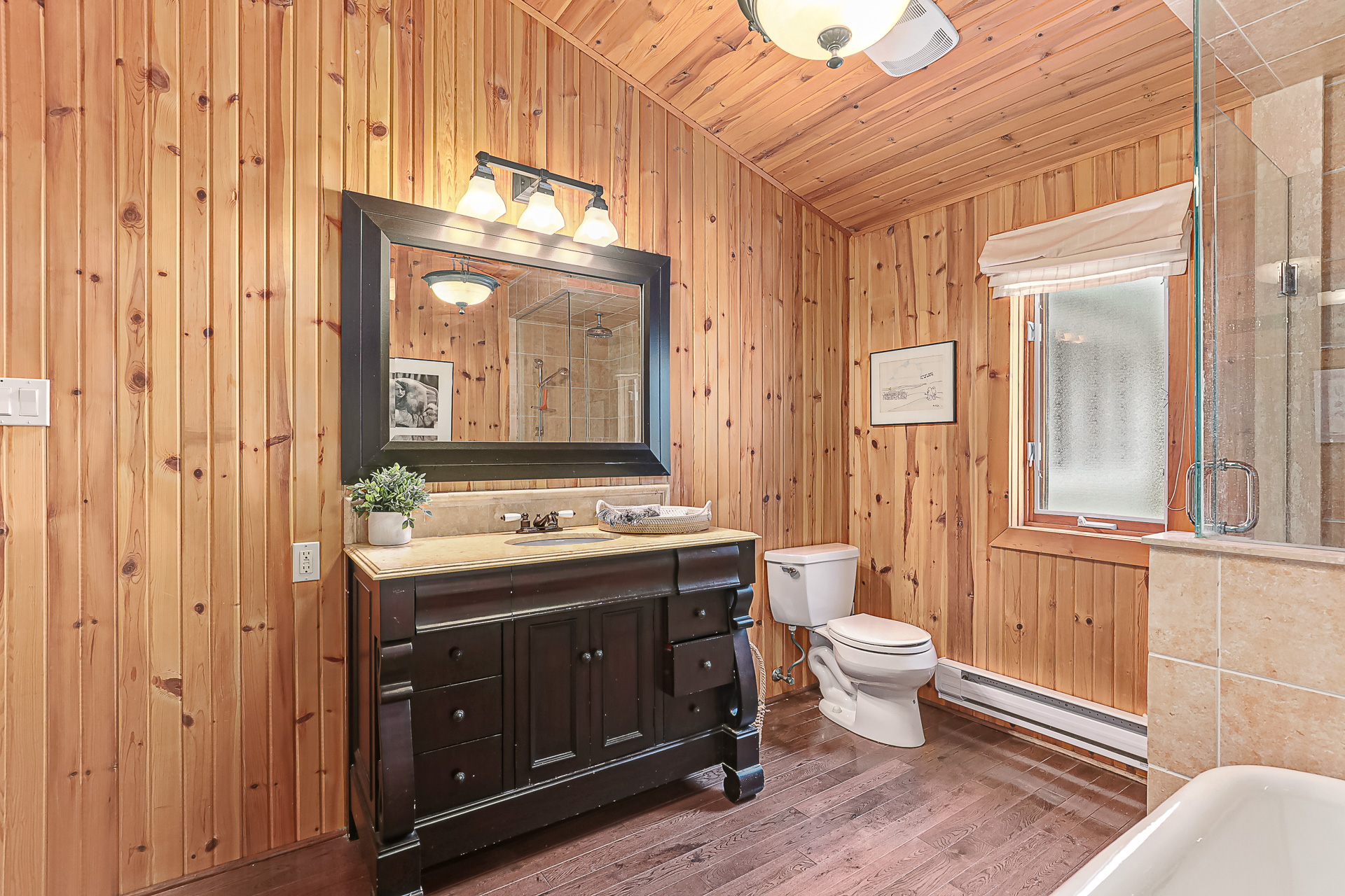 A black bathroom vanity with a black framed mirror above it. To the right, a toilet