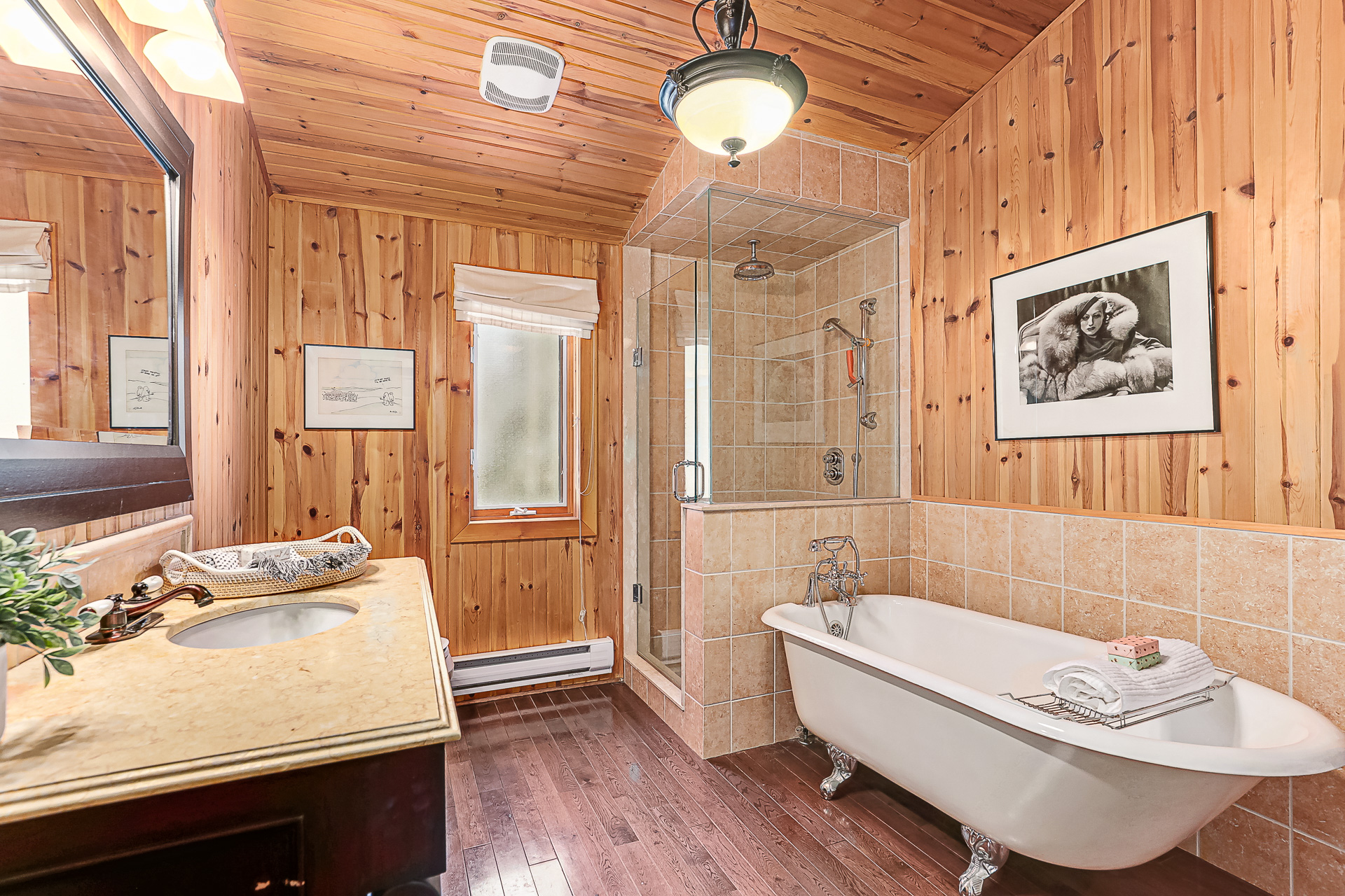 A black vanity faces a glass shower and a white ceramic freestanding bathroom
