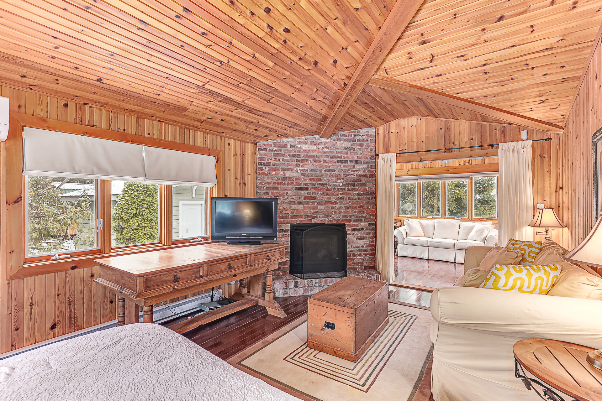 A white couch faces a brick wall with a black fireplace