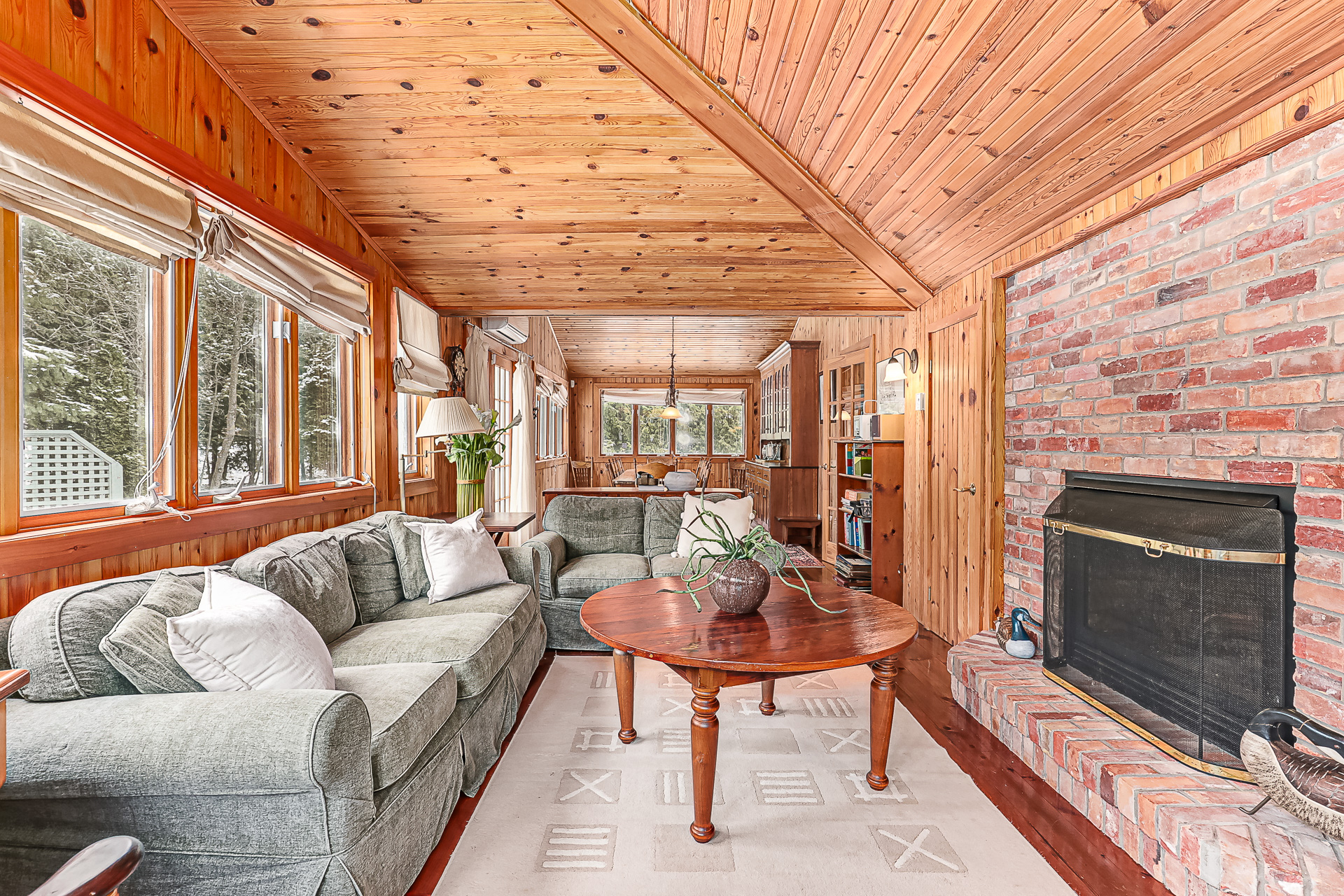 A green velvet couch faces a brick wall with a black fireplace