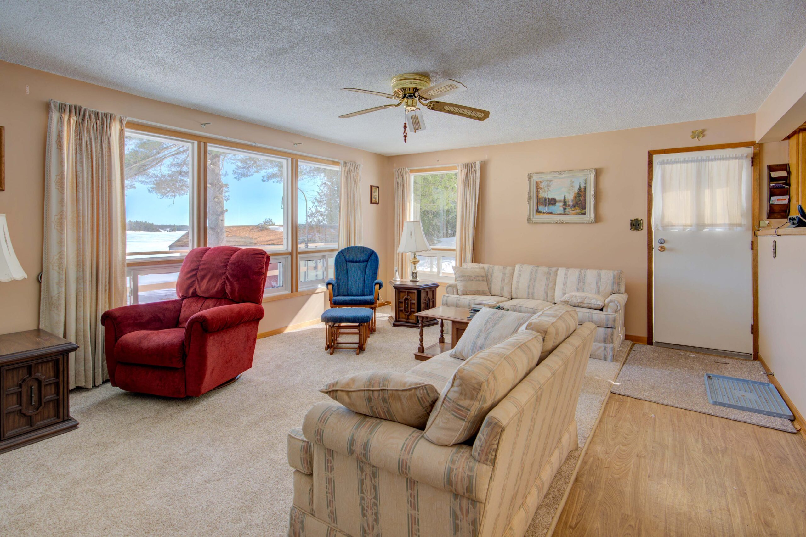 A cream striped couch faces a lake-view window