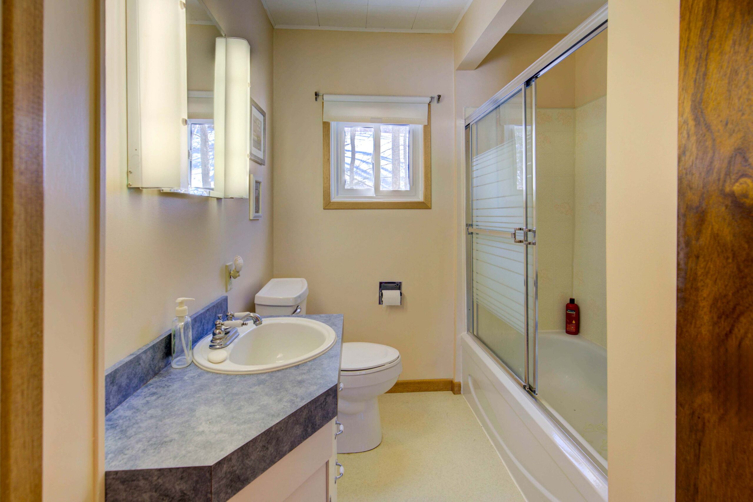 A glass shower faces a white bathroom vanity with grey countertops