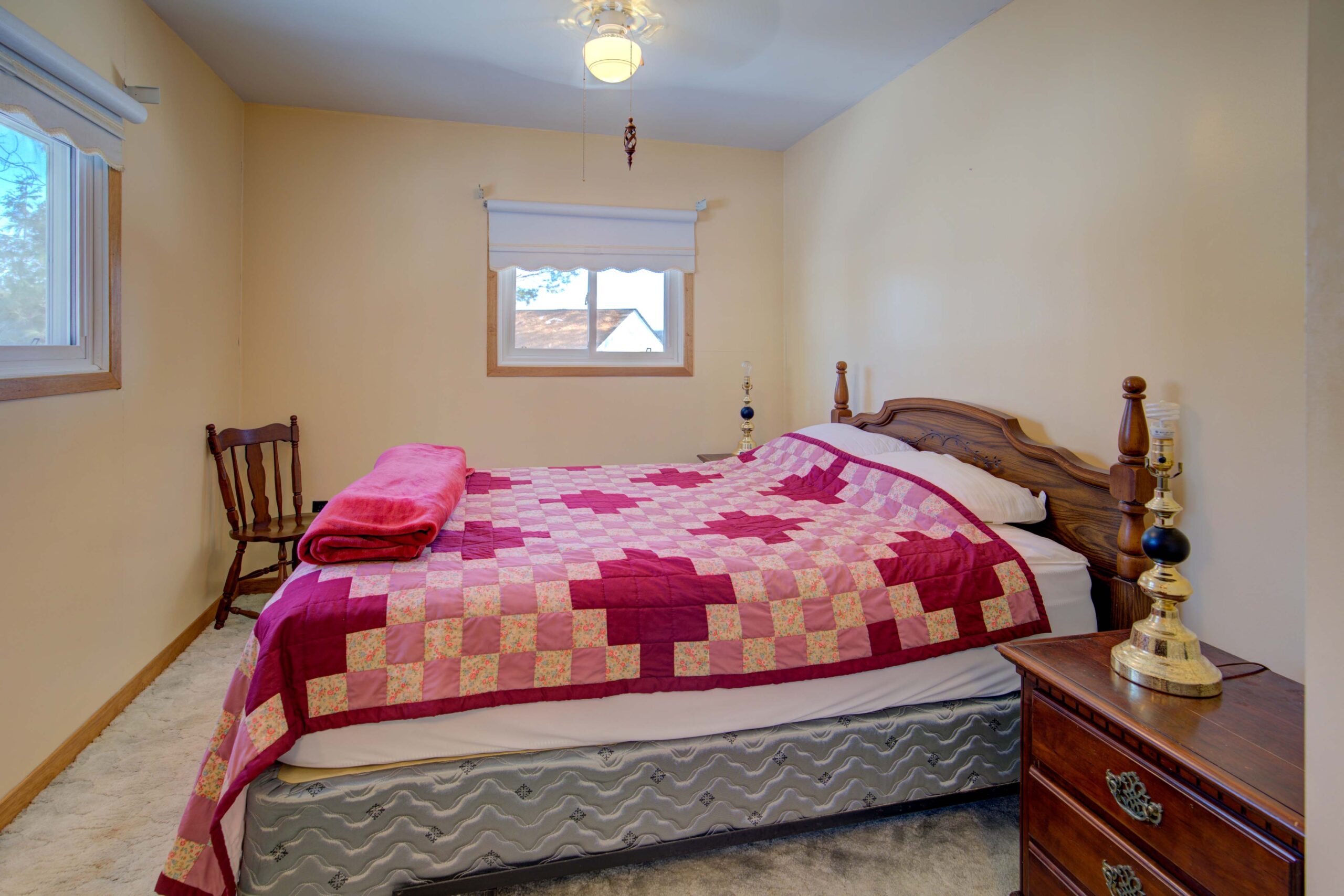 A bed with a pink quilt in a white room
