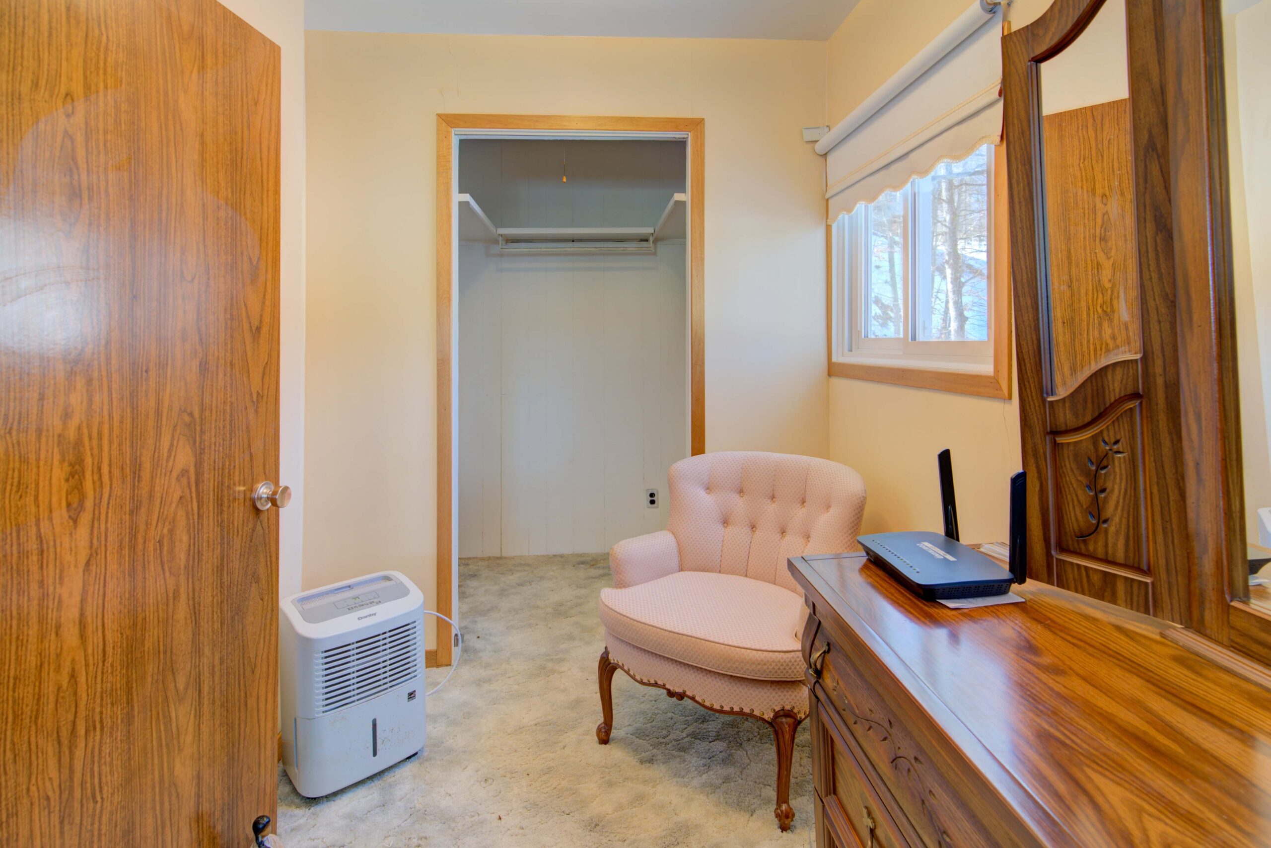 A light pink chair in front of a doorless closet