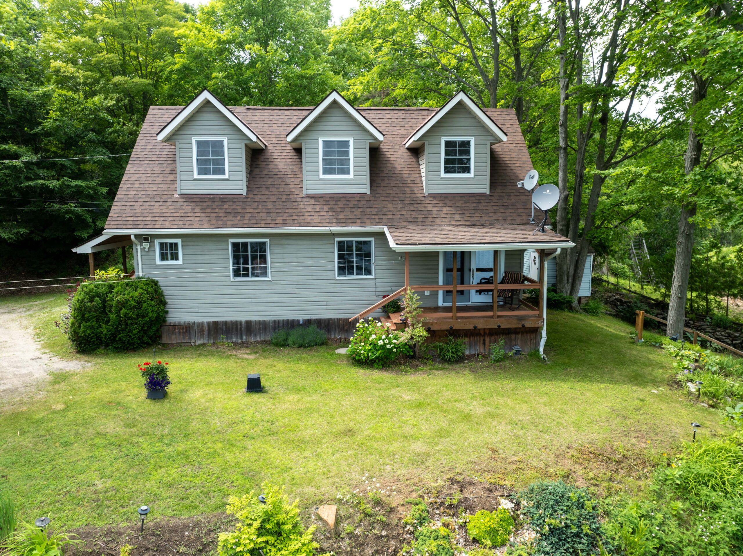A paneled cottage on a lush green yard