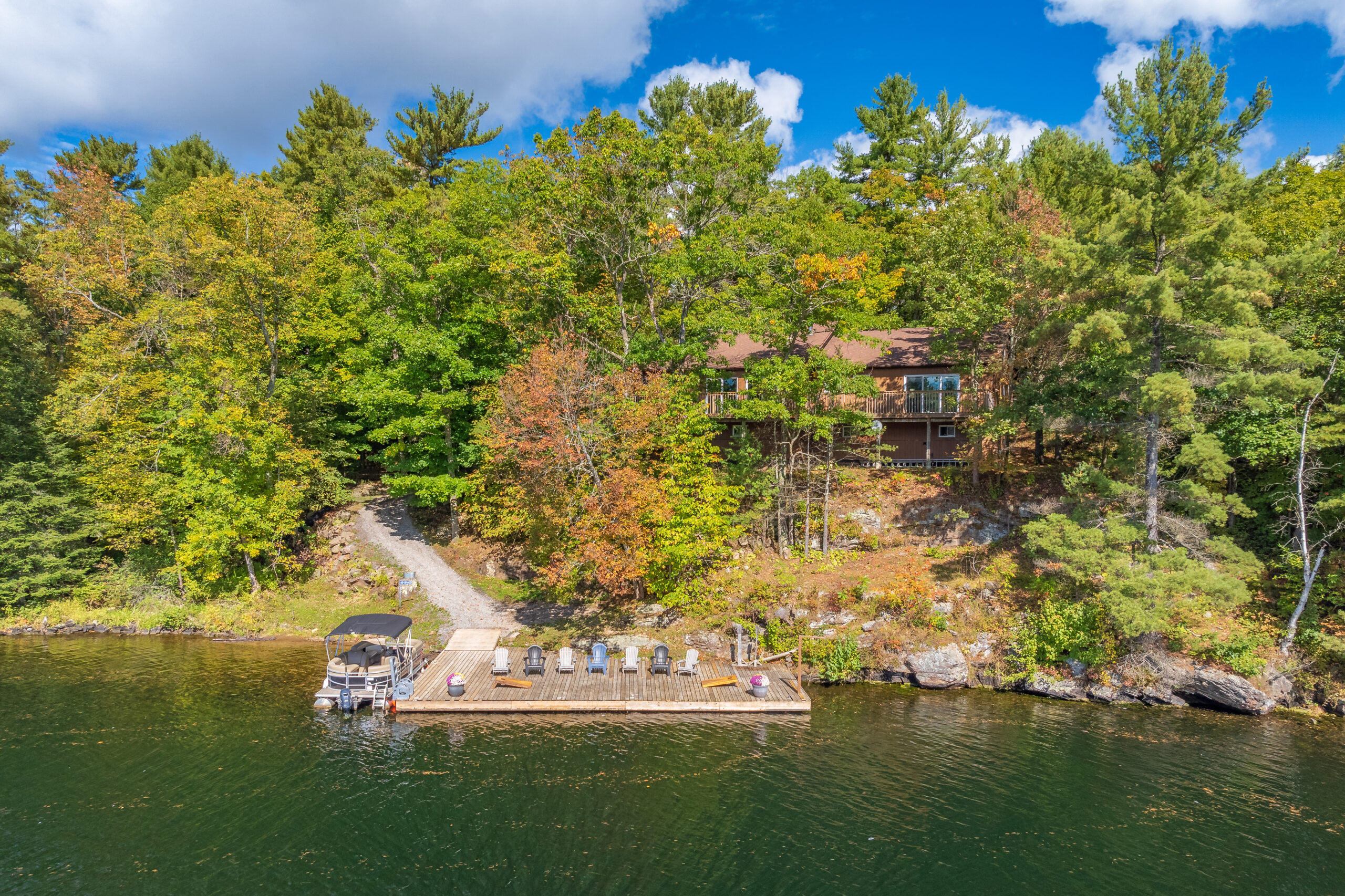 Aerial shot of a Severn River cottage surrounded by trees, with a large dock extending over the water.