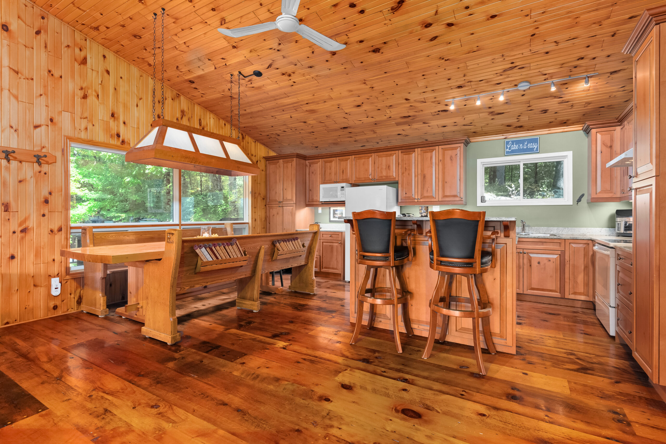 Bright kitchen and dining space with pine walls, hardwood floors, and cathedral ceilings.
