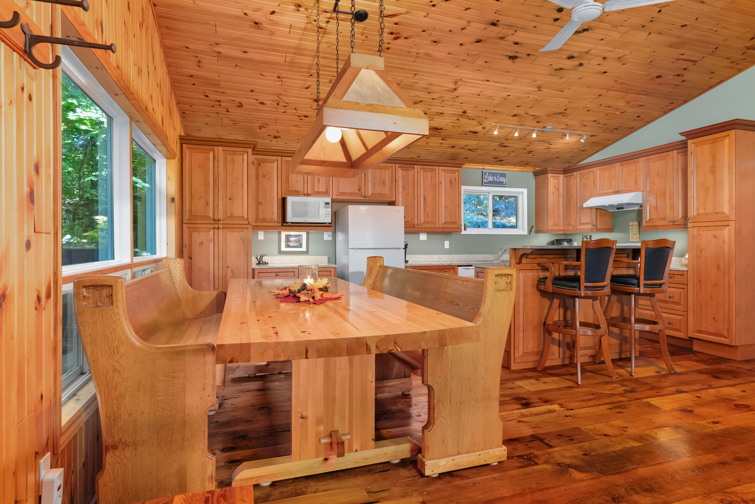 Large kitchen with eat-in dining area, wooden cabinets, and expansive windows.