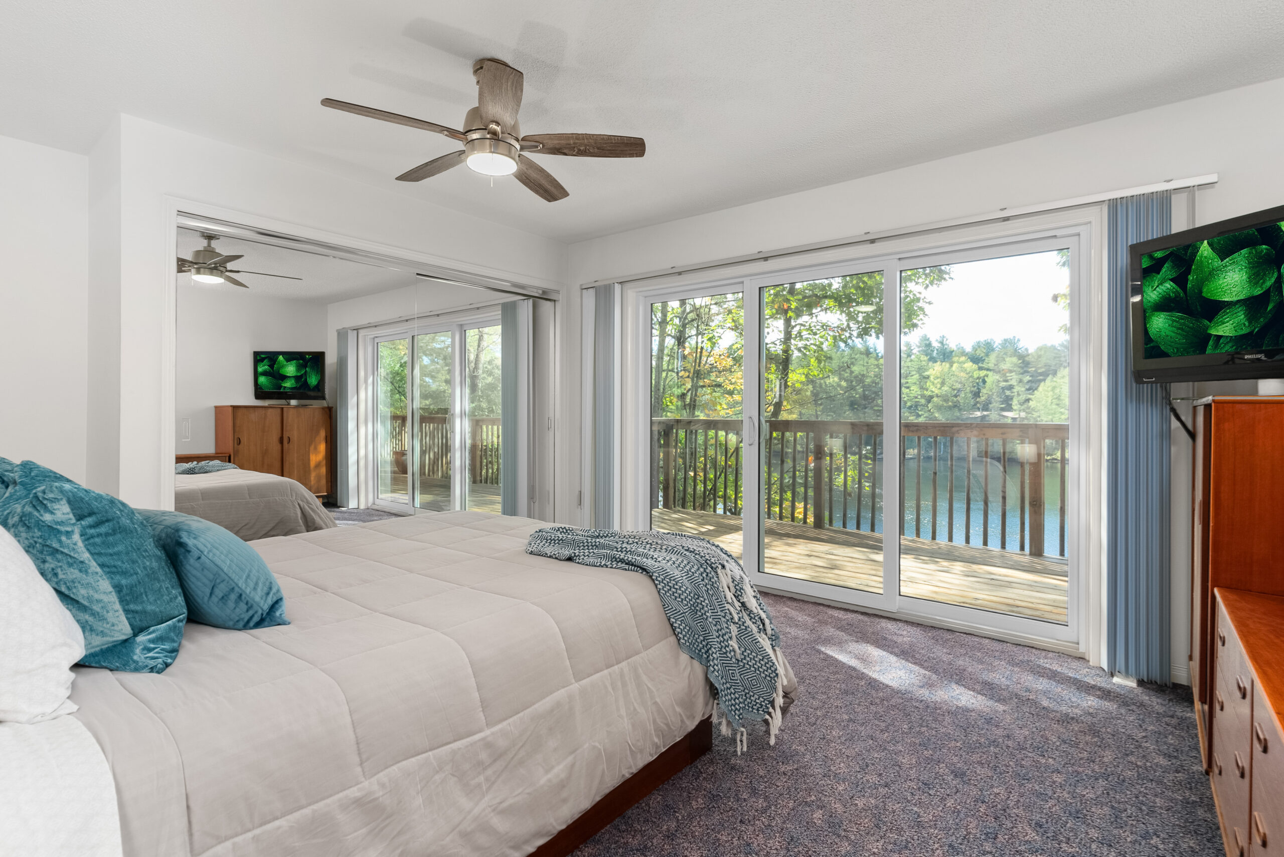 Bright primary bedroom with ceiling fan, patio access, and river-facing windows.