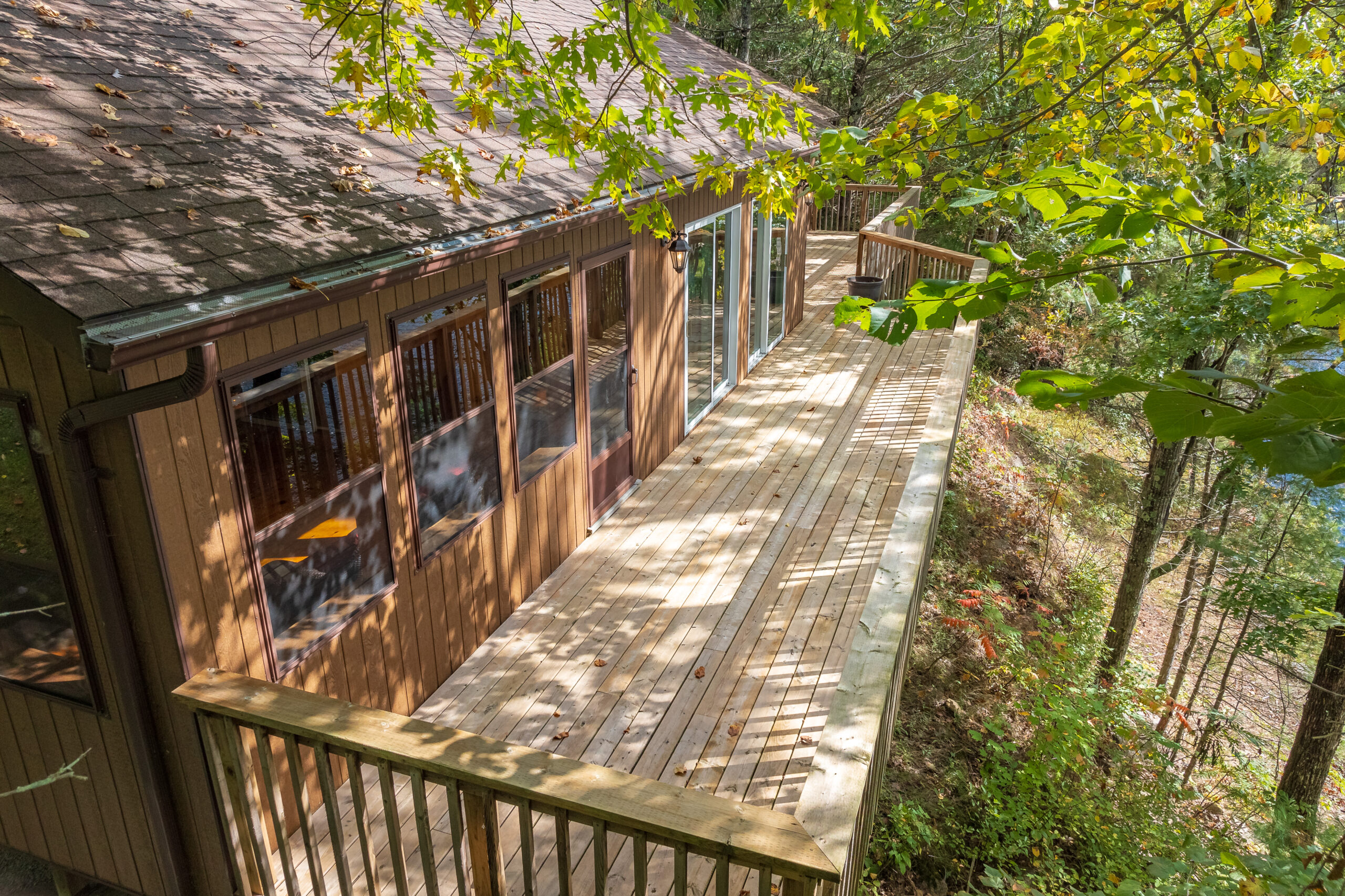 Narrow wooden deck hugging the cottage and facing the wooded lot.