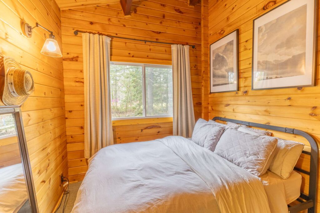 A white bed with white curtains in a wood-paneled room