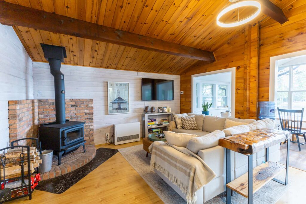 An L-shaped beige couch faces a wood stove