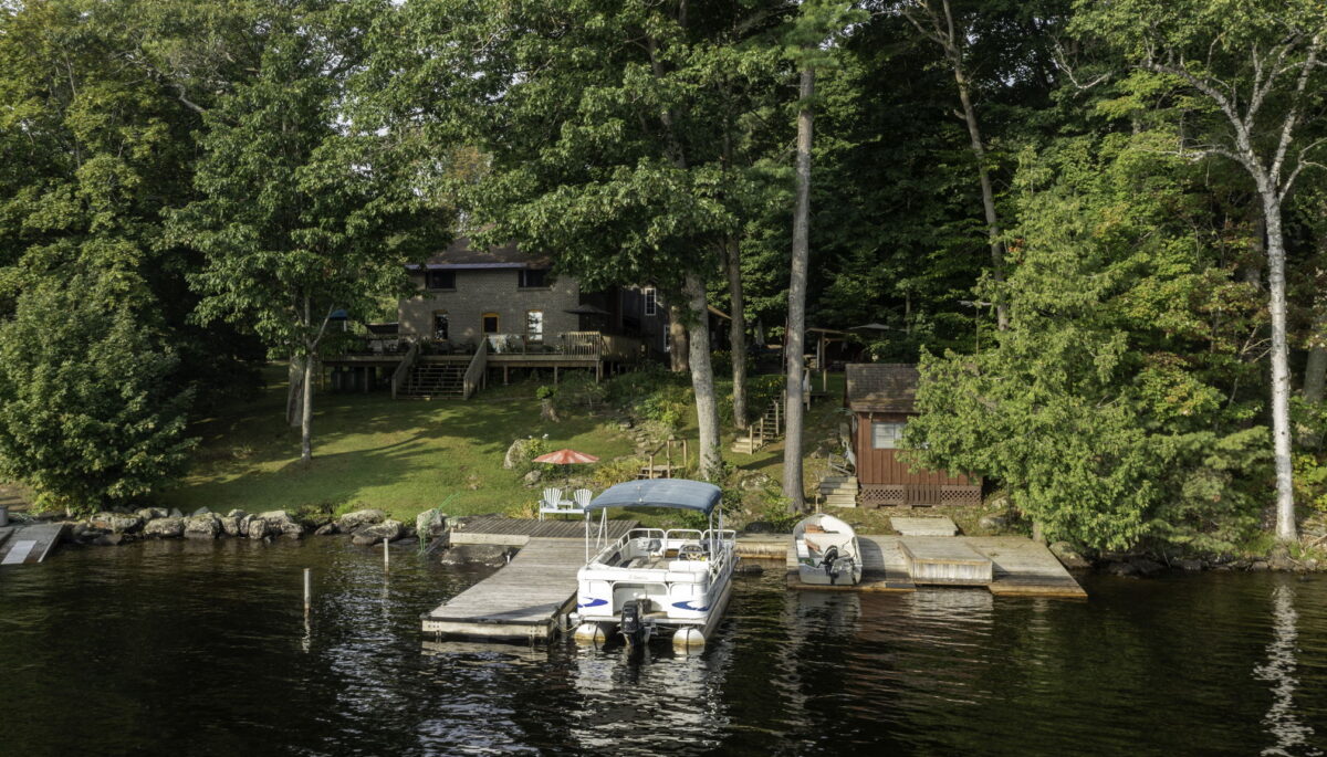 Century farmhouse on Lake Muskoka with wrap-around deck and waterfront docks