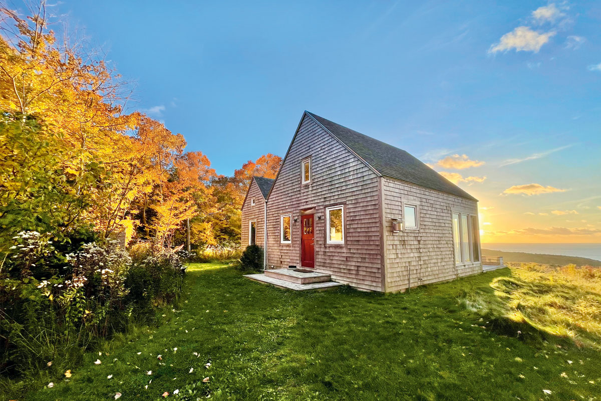 The wooden exterior of Cape cottage, with a red door