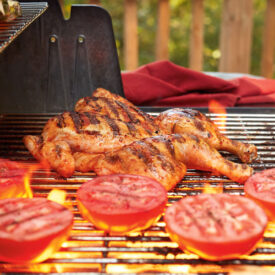 Spatchcocked chicken and tomatoes grilling on a barbecue
