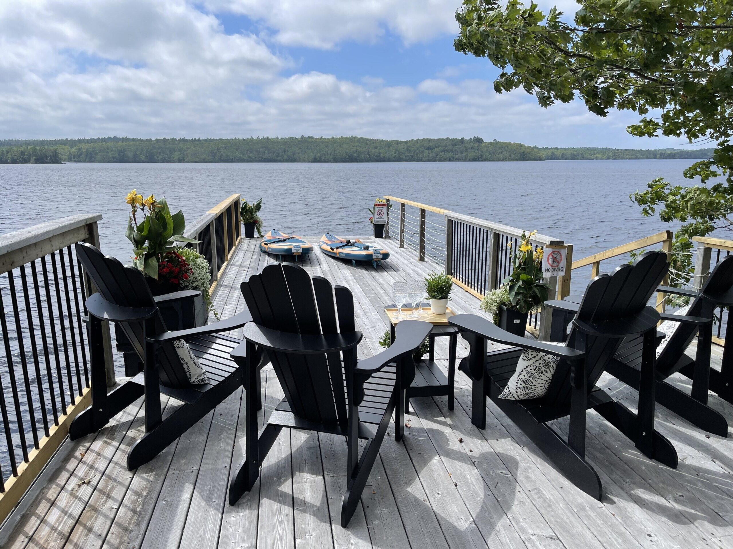 Black Muskoka chairs face the lake on the dock