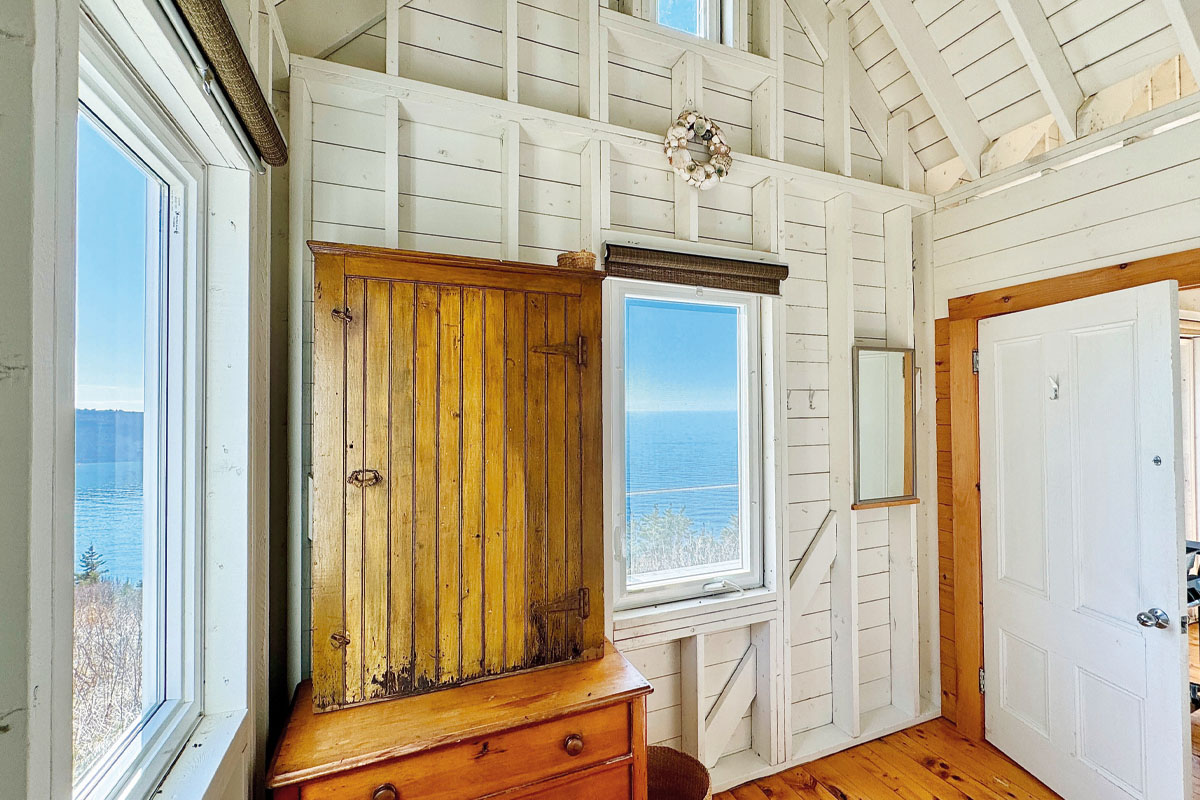 The whitewashed walls of a cottage with a window overlooking the ocean