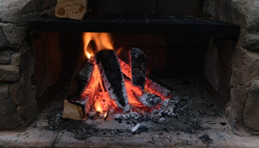 A cozy fireplace with a burning log in it