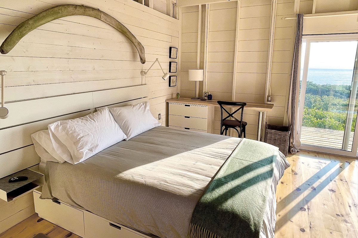 A bedroom in TwoBySea cottage with white bedding and a green blanket