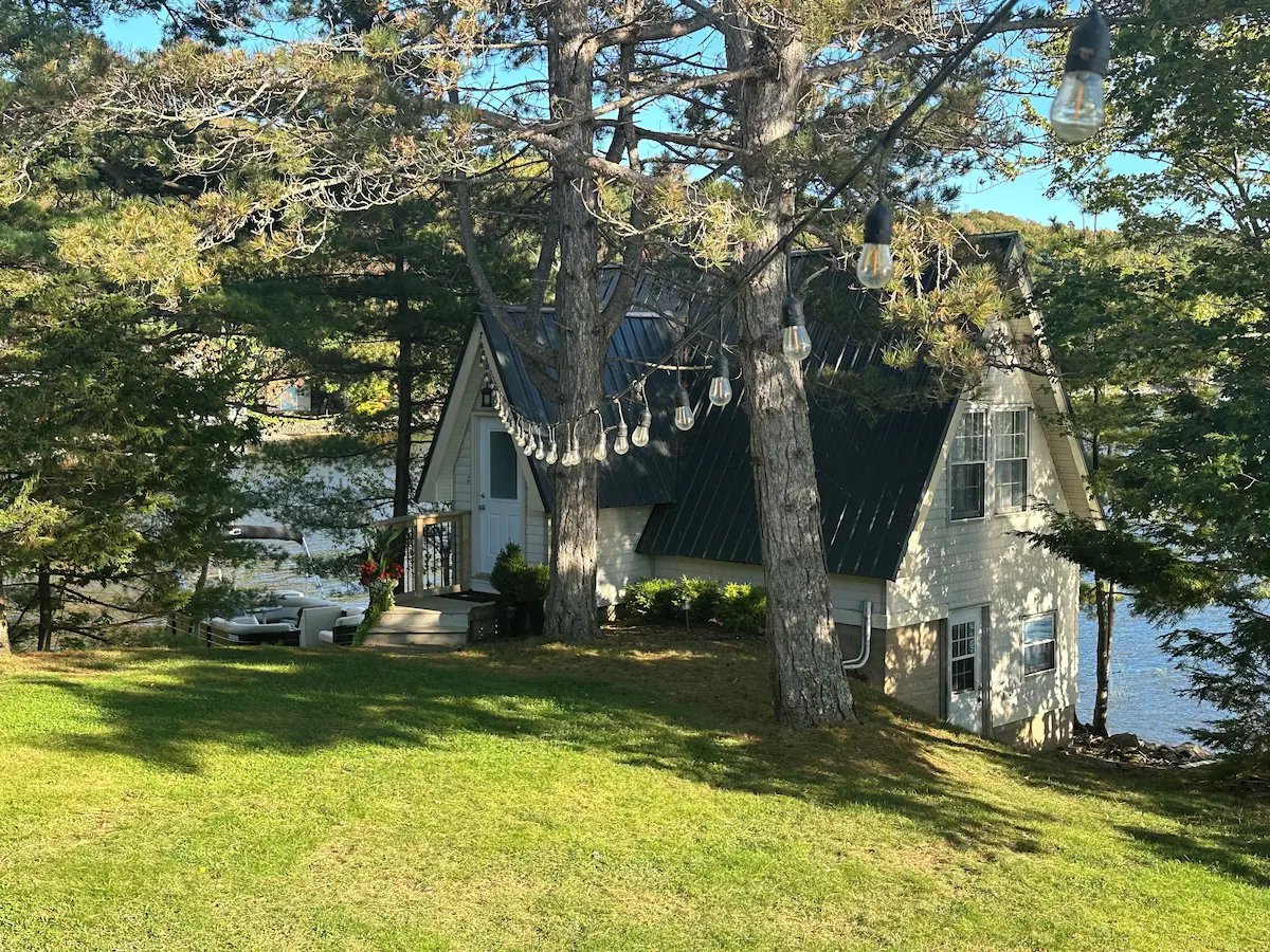 A beige guesthouse with a grey roof in a green yard