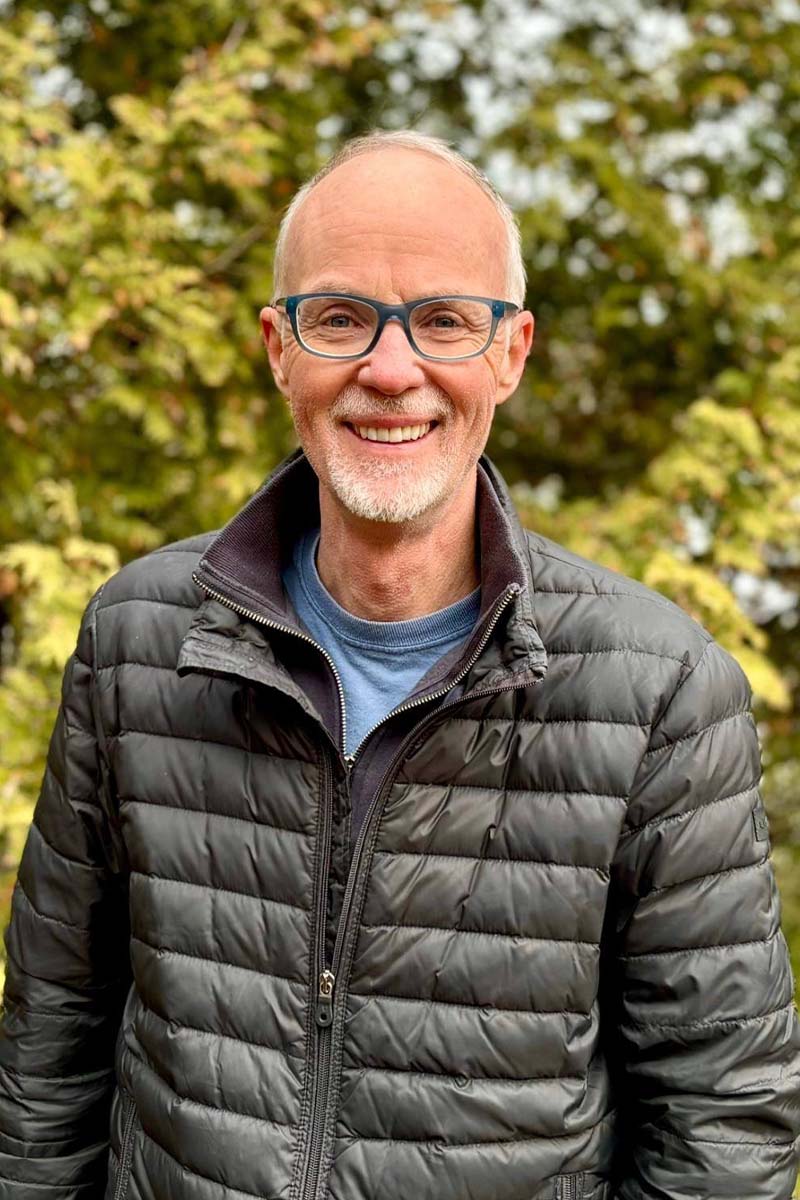 A man standing outdoors at his cottage.