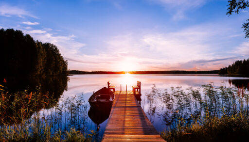 A dock and boat on a lake at sunset