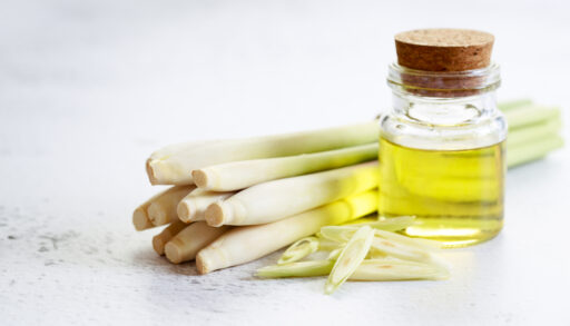 A bottle of lemongrass essential oil and fresh lemongrass