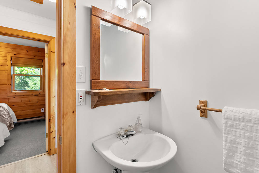 Clean and bright bathroom with sink, toilet, and wood trim