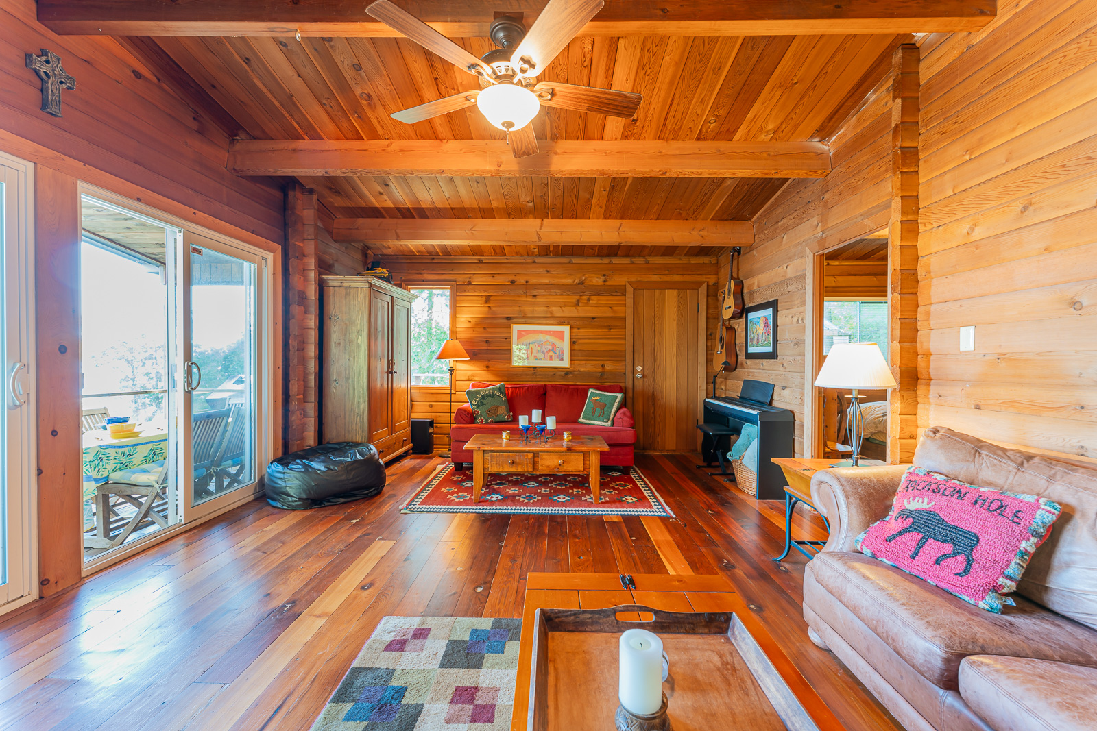 A red couch with a wood coffee table at the end of a wood paneled room