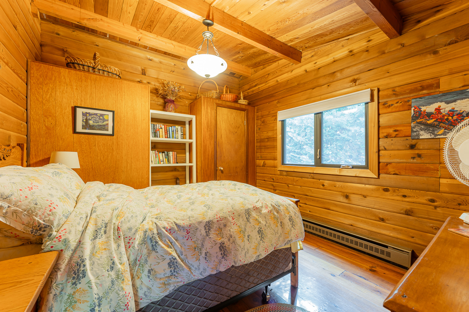 A white floral bed facing a window in a wood bedroom