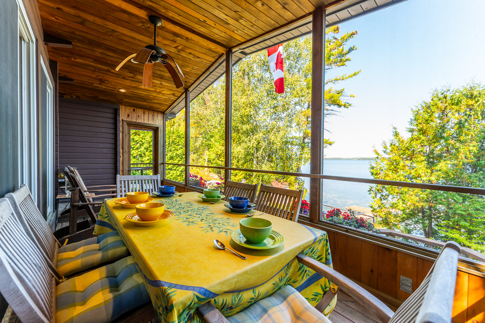 A dining table with a blue and yellow tablecloth next to huge lake-facing windows
