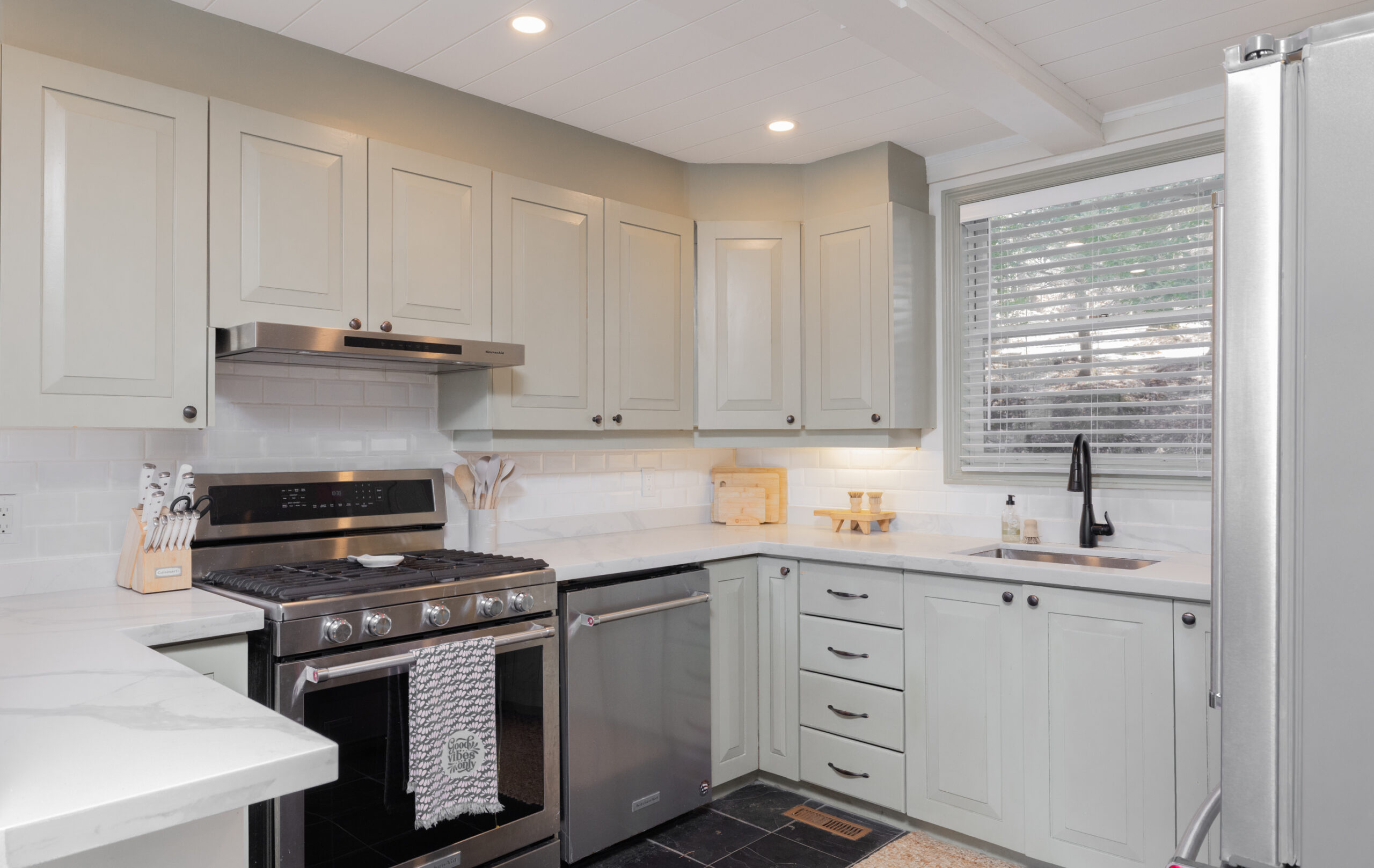A kitchen with blue-grey cabinets and a stainless steel stove