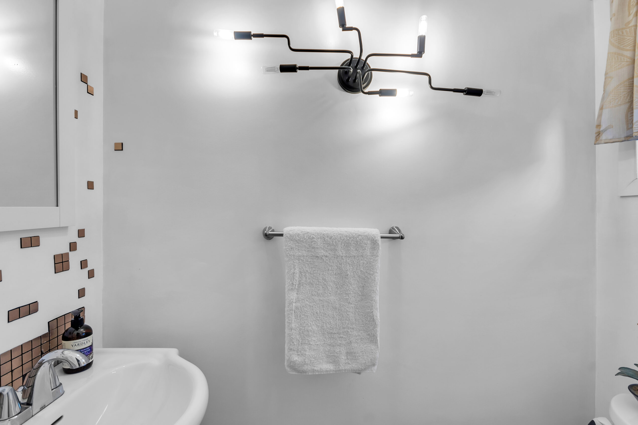 A white bathroom with a white towel hung up beside the sink