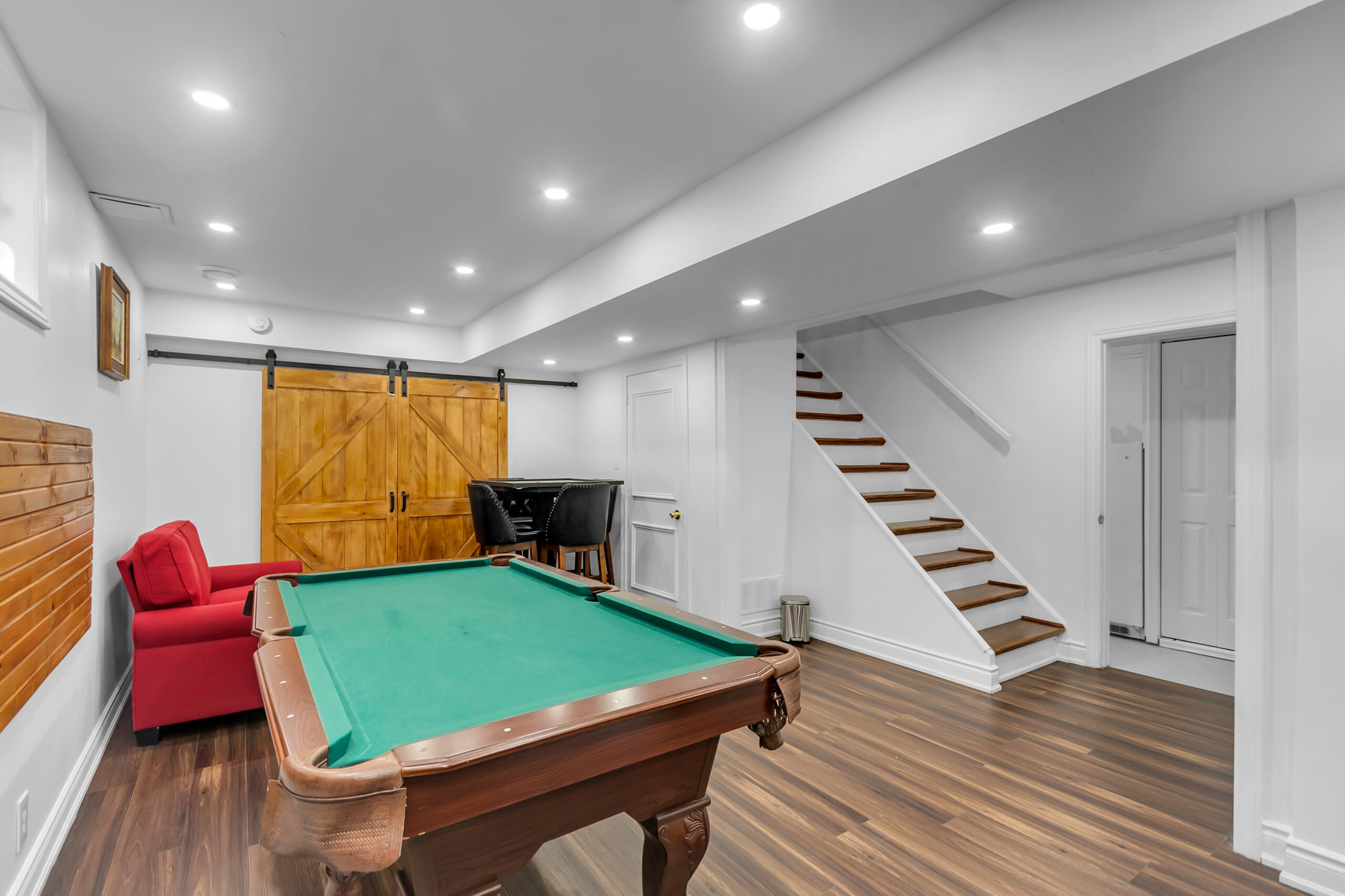 Steps lead down into a white bedroom with a pool table