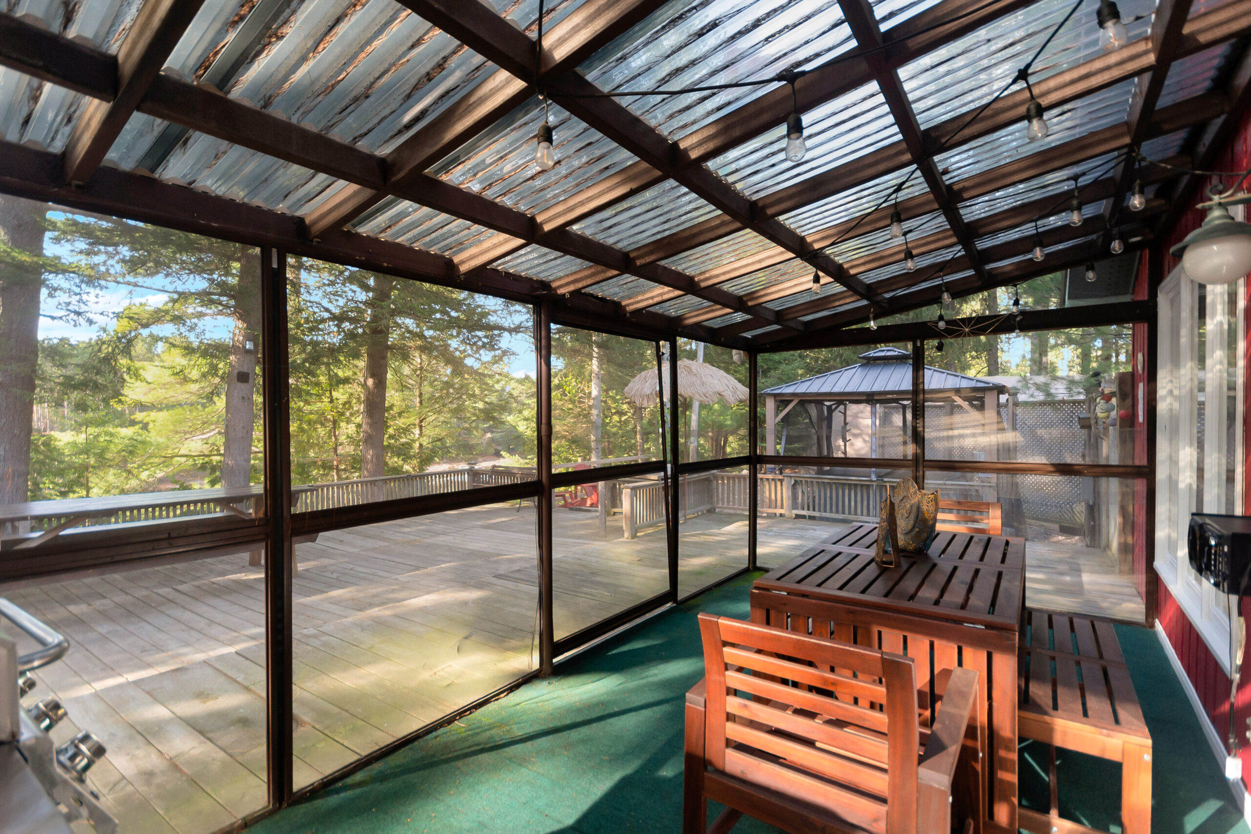 A screened-in sun room with green flooring